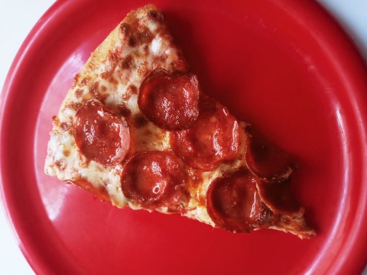 A slice of pepperoni pizza on a red plate