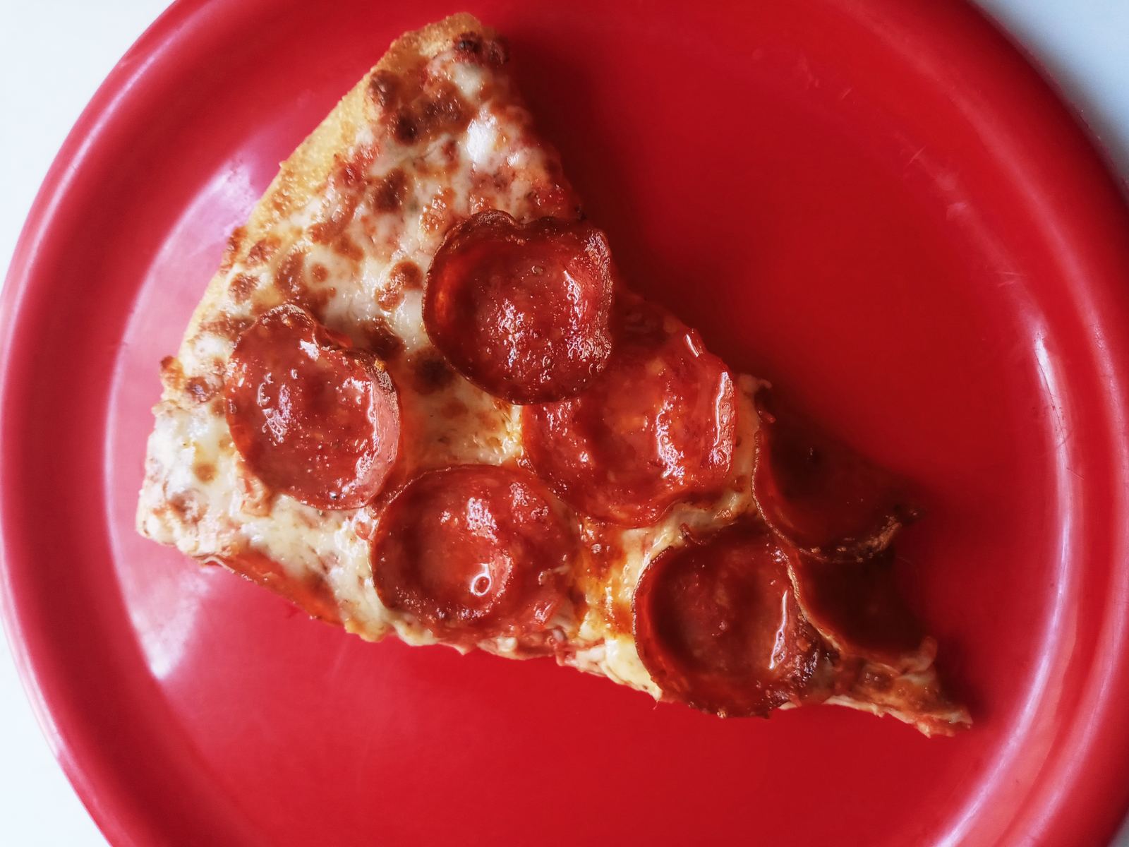 A slice of pepperoni pizza on a red plate